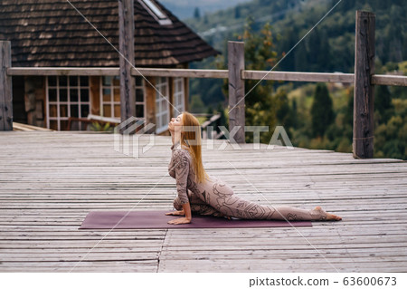 A woman practices yoga at the morning in a terrace on a fresh air. 63600673