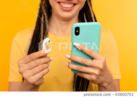 Closeup view of phone and airpods on the yellow background. 63600701