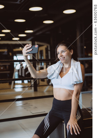 Young sporty woman taking a selfie with mobile phone for social networks at gym. 63600768