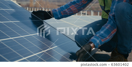 Technicians installing solar panels on metal stand 63601402