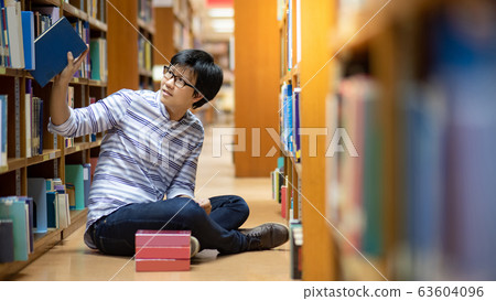 Smart Asian man student reading book in library Smart Asian man student reading book in library 63604096