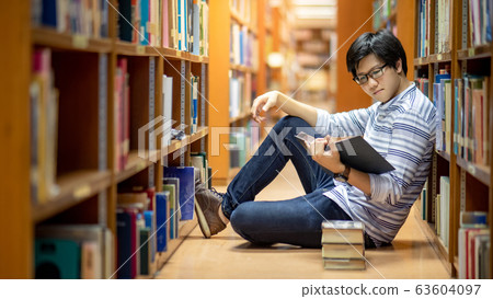 Smart Asian man student reading book in library Smart Asian man student reading book in library 63604097
