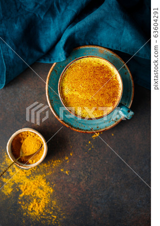 Top down view of turmeric latte cup on a textured dark background. Top down view of turmeric latte cup on a textured dark background. 63604291