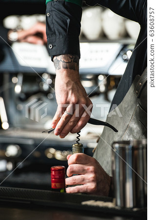 Opening a wine bottle with corkscrew in a bar 63608757