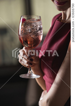 woman holds relaxing alcoholic pink coctail with a 63608790