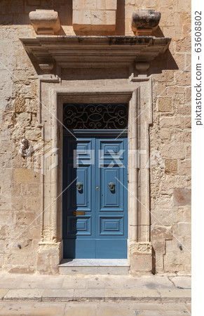 Vintage blue wooden door in yellow stone wall 63608802