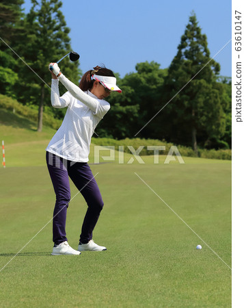 Woman hitting the tee shot Woman hitting the tee shot 63610147