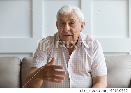 Head shot serious older man looking at camera and talking Head shot serious older man looking at camera and talking 63610712
