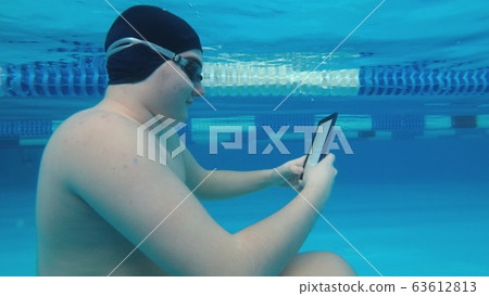 The guy is reading an electronic book underwater. 63612813