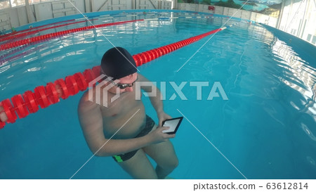 The guy is reading an electronic book underwater. The guy is reading an electronic book underwater. 63612814