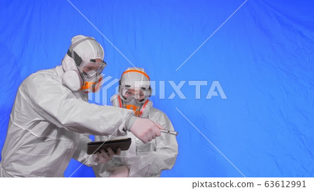 Scientist virologist in respirator makes write in an tablet computer with stylus. Man and woman wearing protective medical mask. Chroma key blue. 63612991