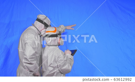 Scientist virologist in respirator makes write in an tablet computer with stylus. Man and woman wearing protective medical mask. Chroma key blue. 63612992