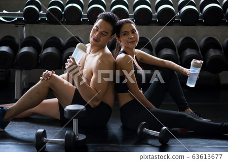couple drink after dumbbell exercise in gym 63613677