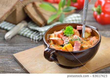 Hot potato goulash with bacon and Vienna sausages served in a ceramic bowl with dark baked bread Hot potato goulash with bacon and Vienna sausages served in a ceramic bowl with dark baked bread 63617423