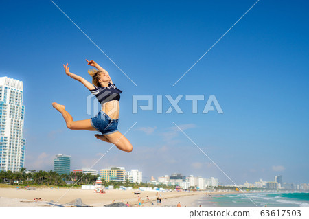 Beautiful girl jump with South Beach on background, Miami Beach. Florida. Concept of happiness and freedom Beautiful girl jump with South Beach on background, Miami Beach. Florida. Concept of happiness and freedom 63617503