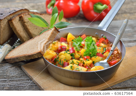 Hot vegetarian potato goulash served in an iron pan with delicious dark baked farmhouse bread Hot vegetarian potato goulash served in an iron pan with delicious dark baked farmhouse bread 63617564