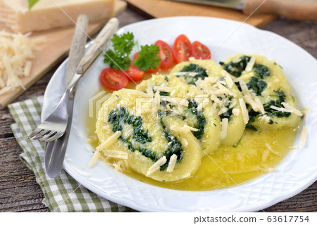 Delicious South Tyrolean potato spinach roulade with shaved parmesan cheese and melted butter 63617754