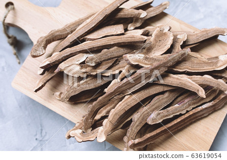 Slices of dried lingzhi mushroom, also called Reishi, on a wooden board 63619054