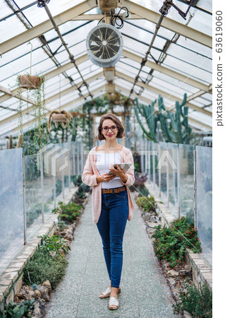 Woman researcher standing in greenhouse, using tablet. Woman researcher standing in greenhouse, using tablet. 63619060