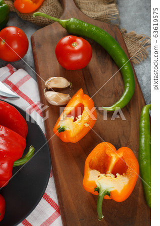 Chilies, yellow peppers, tomat and garlics on a wooden board. Top view. Chilies, yellow peppers, tomat and garlics on a wooden board. Top view. 63619575