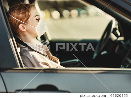 Woman in medical mask sitting in car. 63620563
