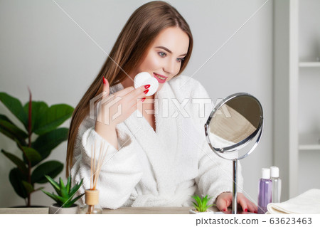 Cute young woman puts makeup on the face in the bathroom 63623463
