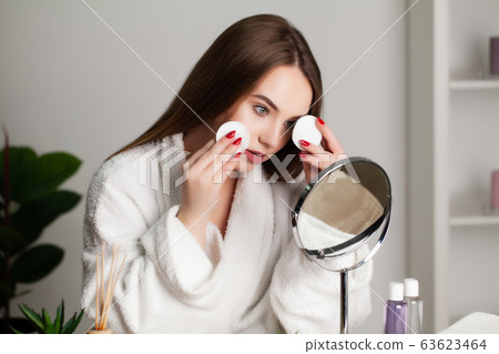 Cute young woman puts makeup on the face in the bathroom Cute young woman puts makeup on the face in the bathroom 63623464