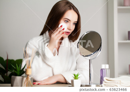Cute young woman puts makeup on the face in the bathroom 63623466