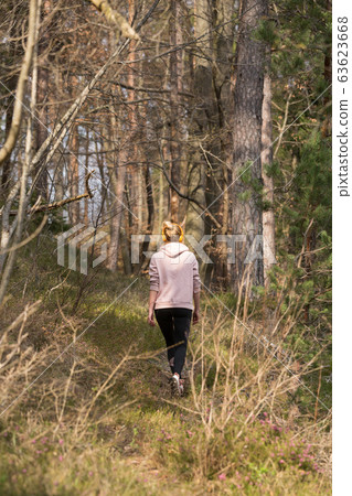 Rear view of active sporty woman listening to the music while running in autumn fall forest. Female runner training outdoor. Healthy lifestyle image of young caucasian woman jogging outside 63623668