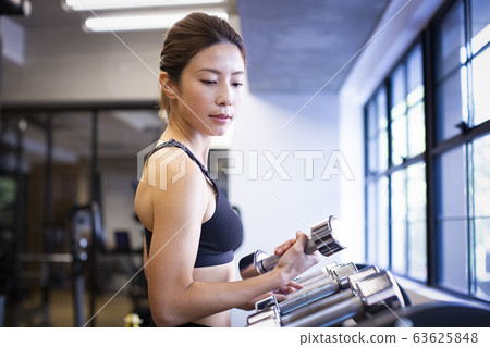 Woman choosing dumbbells 63625848