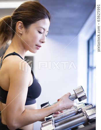 Woman choosing dumbbells Woman choosing dumbbells 63625991