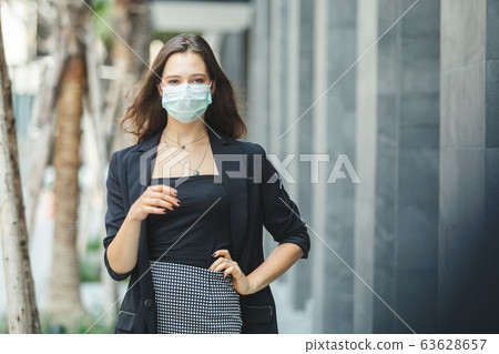 businesswoman in suits wearing medical mask walking on city street. businesswoman in suits wearing medical mask walking on city street. 63628657
