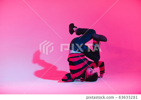 Young Man in a Jumper Dancing Contemporary Dance in Studio. Breakdancing. Dance School Poster. Copy Space. Battle competition announcement. Pink and Blue Background. 63633281