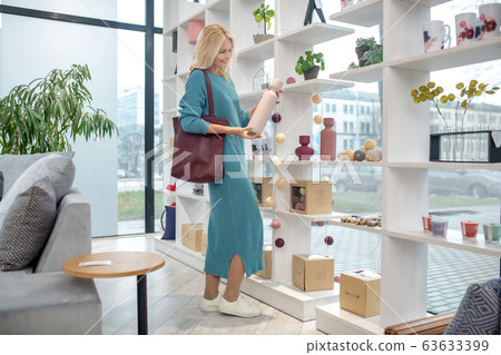 Woman in a bright room with a white vase in hands. Woman in a bright room with a white vase in hands. 63633399