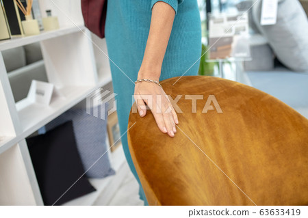 Female hand lying on a velor orange armchair. 63633419