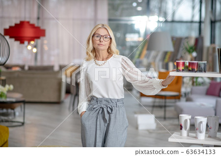 Serious woman with glasses standing in a large hall. 63634133