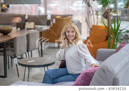 Woman talking on smartphone sitting on a sofa. 63634210