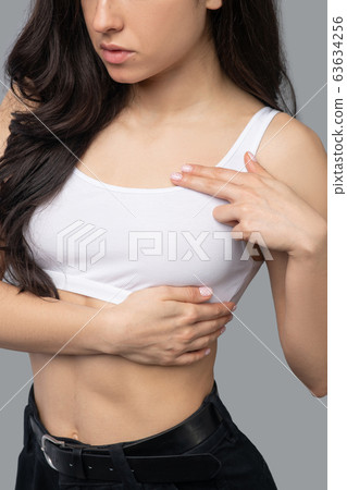 Beautiful dark-haired girl in a white top measuring her body 63634256