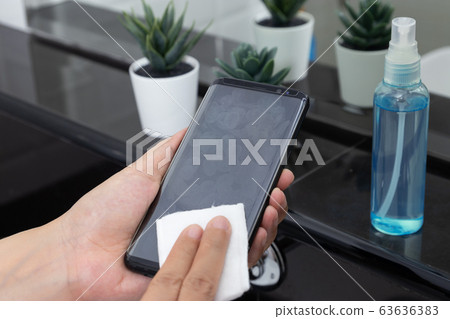 disinfect, sanitize, hygiene care. cleaning fingerprint on mobile phone touch screen for disinfection, prevention of germs spreading during infections of COVID-19 coronavirus 63636383