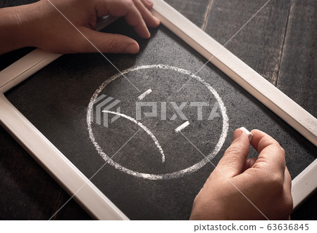 Hand drawing sad smiley face on black chalk board. 63636845