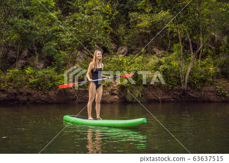 SUP Stand up paddle board woman paddle boarding on lake standing happy on paddleboard on blue water 63637515