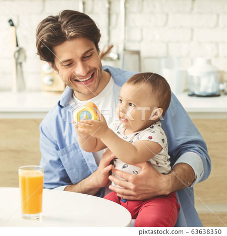 Cheerful daddy playing with his adorable baby at kitchen Cheerful daddy playing with his adorable baby at kitchen 63638350