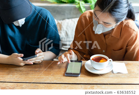 Two womans in protective mask prevent Covid-19 using cell phone and drinking lemon tea in cafe. 63638552