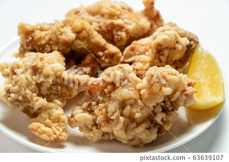 Fried chicken thigh with cut lemon. (White plate, white background) 63639107