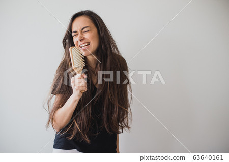 Woman brushes her long hair with wooden hairbrush  63640161