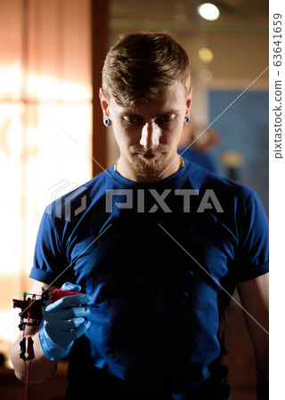 Master holding in the hands equipment for making tattoo art. 63641659