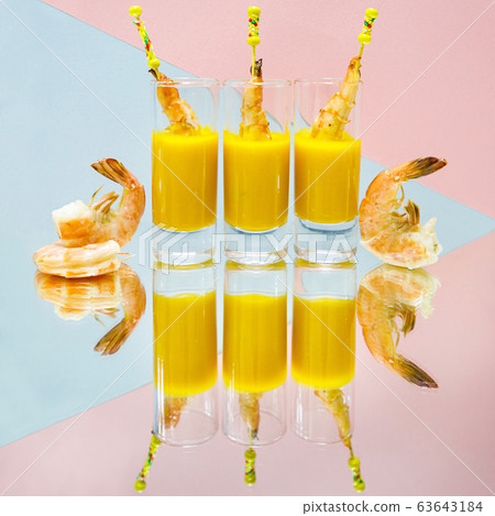 Shrimp in mango sauce in glass on the mirror surface on the pink background 63643184