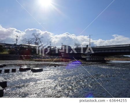 River and bridge with stepping stones in the morning sun and sparkling water surface River and bridge with stepping stones in the morning sun and sparkling water surface 63644255