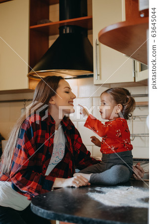 Social Distancing and Self-Isolation, stay home, quarantine, families self-isolating together for Novel Coronavirus COVID-19. Mom and toddler daughter play in the kitchen. Social Distancing and Self-Isolation, stay home, quarantine, families self-isolating together for Novel Coronavirus COVID-19. Mom and toddler daughter play in the kitchen. 63645044