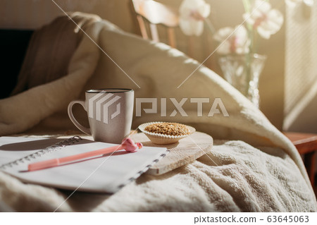Morning routine, Miracle Morning, new day concept. Best ritual and habits. Cup of coffee, whole grain cookies, open notepad on wooden tray on the bed in the sun. 63645063